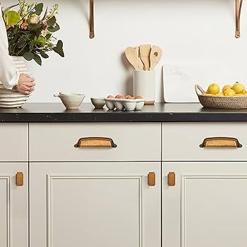 Helle Küchenschränke mit eleganten Knöpfen und Muschelgriffen aus Messing.