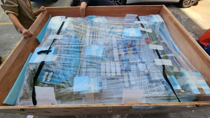 Ein großes Architekturmodell, sicher verpackt in einer Holzkiste mit Schutzfolie.