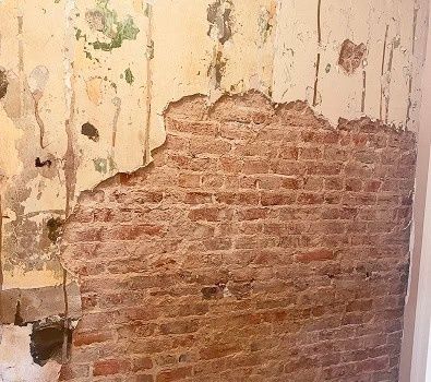 Freigelegte historische Ziegelwand unter abgeplatztem Putz im Altbau