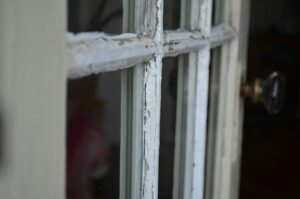 Nahaufnahme eines verwitterten, weiß gestrichenen historischen Kastenfensters