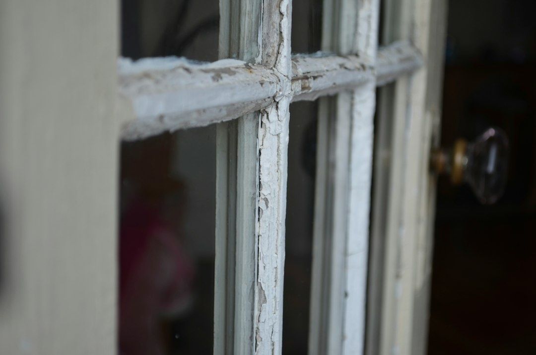 Nahaufnahme eines verwitterten, weiß gestrichenen historischen Kastenfensters